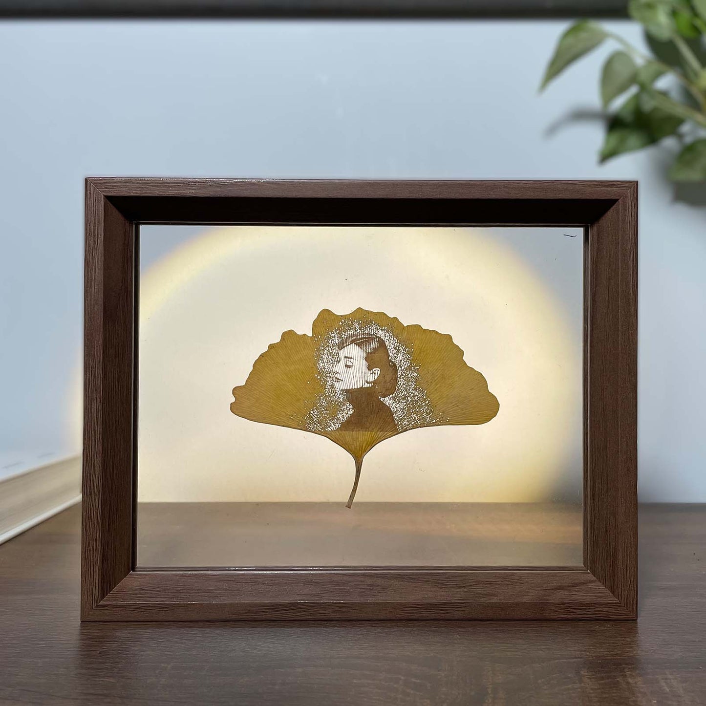 Framed artwork with a silhouette of Audrey Hepburn on a ginkgo leaf against a light background