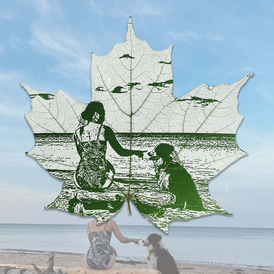 A skeletonized maple leaf of a woman with a dog on a beach