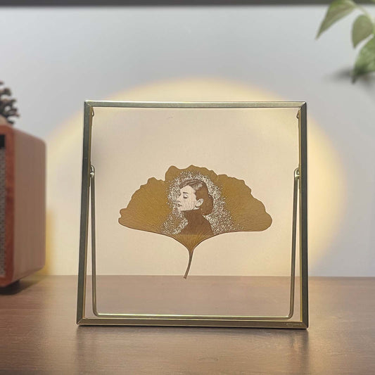 Framed artwork of Audrey Hepburn's face on a ginkgo leaf with a blurred background