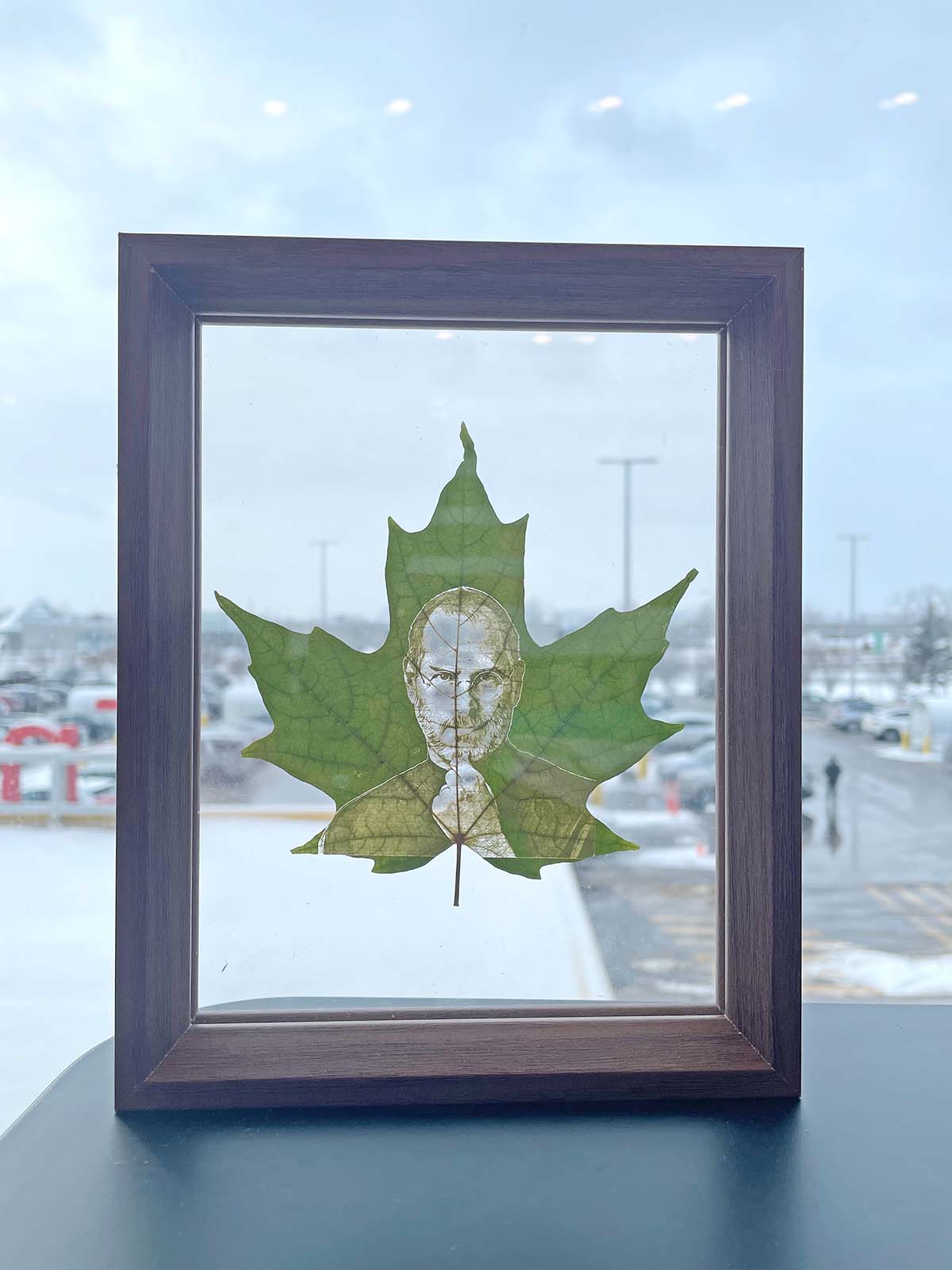 A custom maple leaf engraving featuring a single person's portrait, elegantly framed and displayed against a snowy Canadian street, a unique memorial keepsake available on our Canadian e-commerce site.